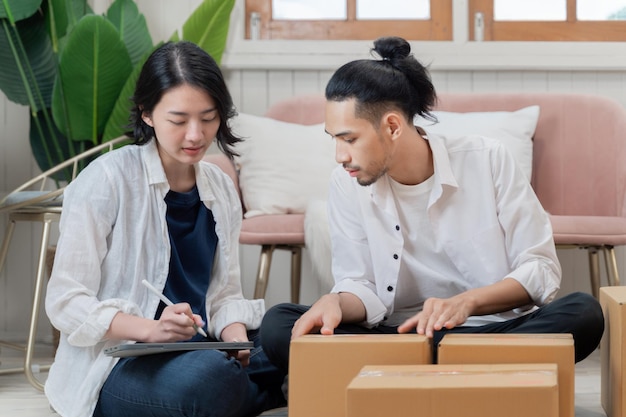 Giovani coppie che imballano scatole di cartone a casa nuova. Casa in movimento. parcheggio per la consegna. paio di articoli da imballaggio per l'invio. Concetto di piccola impresa di persone da vendere per lo shopping online.