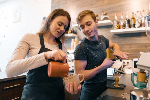 Giovani coppie che lavorano vicino a macchine da caffè, facendo bevande