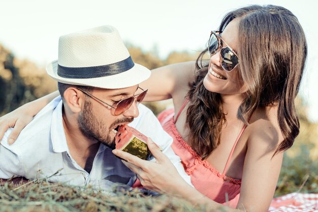 Giovani coppie che mangiano anguria su una data di picnic