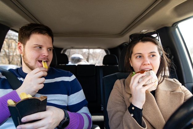 Giovani coppie che mangiano fast food in macchina