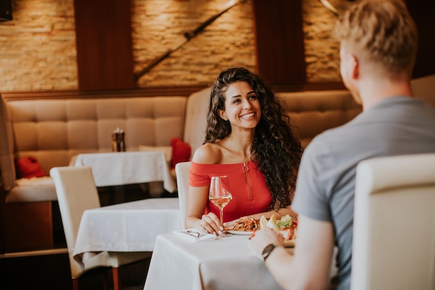 Giovani coppie che pranzano con vino bianco nel ristorante