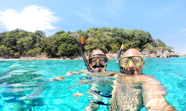 Giovani coppie che prendono selfie nello scenario tropicale