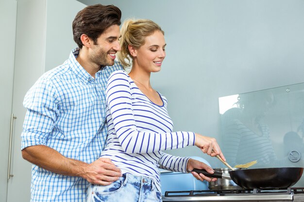 Giovani coppie che preparano insieme alimento nella cucina