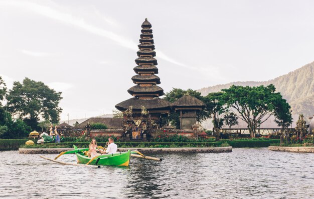 Giovani coppie che remano su una barca di legno a Pura Ulun Danu Bratan