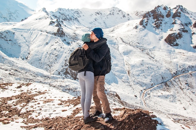 Giovani coppie che si abbracciano su uno sfondo di montagne innevate.