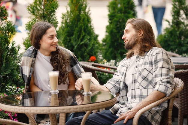 Giovani coppie che si siedono in un caffè all'aperto godendosi un caffè e una conversazione