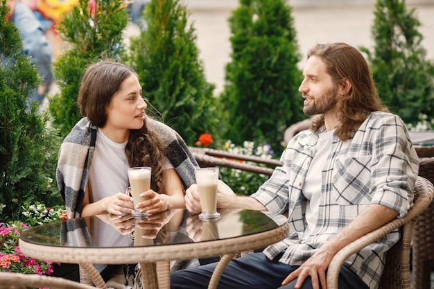 Giovani coppie che si siedono in un caffè all'aperto godendosi un caffè e una conversazione