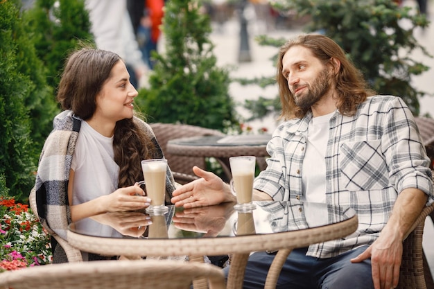 Giovani coppie che si siedono in un caffè all'aperto godendosi un caffè e una conversazione