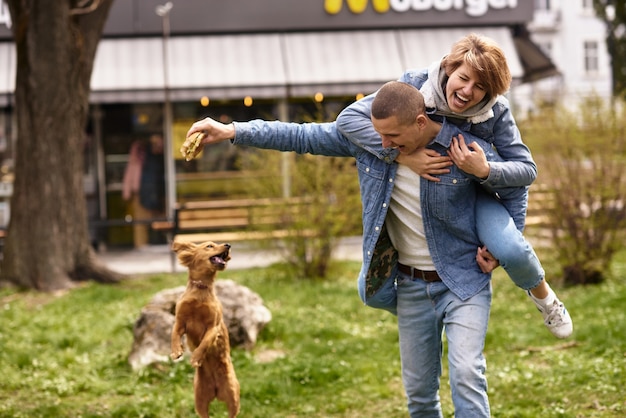 Giovani coppie con il cane che mangia fast food