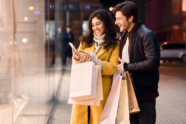 Giovani coppie con smartphone vicino al centro commerciale