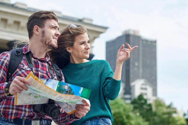 Giovani coppie con una mappa della città. Città facente un giro turistico dei turisti felici con la mappa