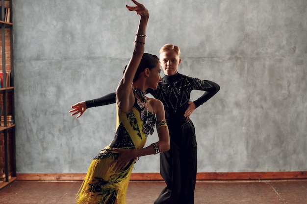 Giovani coppie dei ballerini che ballano il cha-cha-cha di ballo da sala.