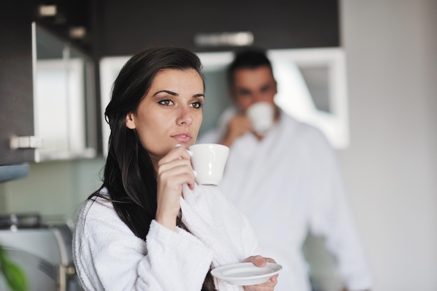 Giovani coppie di amore che prendono la tazza di caffè fresca di mattina nell'appartamento moderno