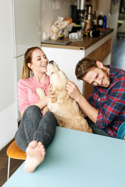 Giovani coppie felici che giocano con il cane a casa