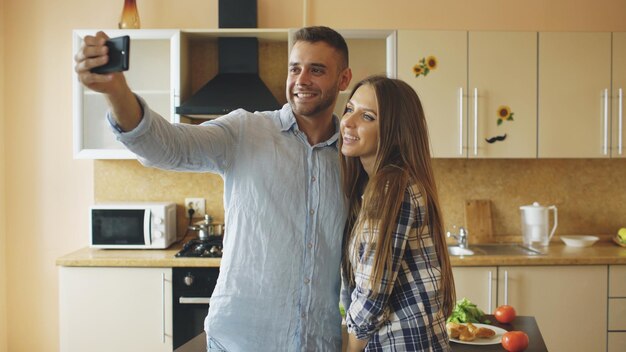 Giovani coppie felici che hanno chat video online in cucina a casa