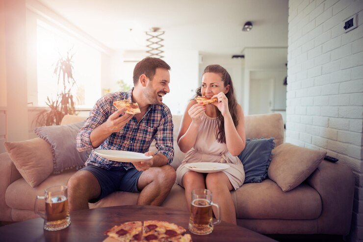Giovani coppie felici che mangiano pizza a casa