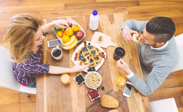 Giovani coppie felici che mangiano prima colazione di mattina