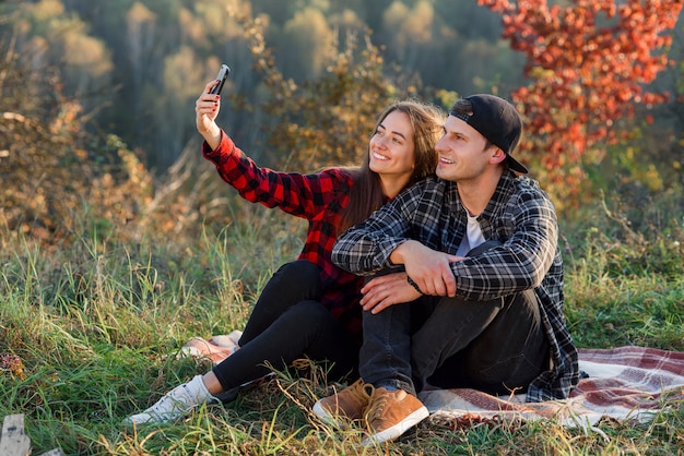 Giovani coppie felici che prendono selfie facendo uso dello smartphone nel parco.