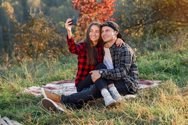 Giovani coppie felici che prendono selfie facendo uso dello smartphone nel parco.