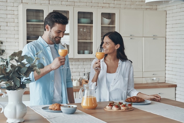 Giovani coppie felici che preparano la colazione insieme mentre trascorrono del tempo nella cucina domestica