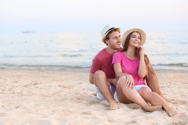 Giovani coppie felici che riposa sulla spiaggia del mare