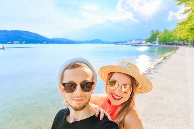 Giovani coppie felici nel lago della montagna che fanno la foto del selfie un ragazzo w