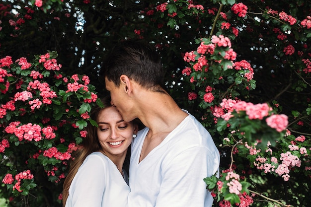 Giovani coppie felici nell'amore all'aperto. amorevole uomo e donna durante una passeggiata in un parco in fiore primaverile