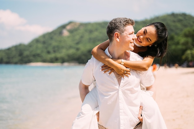 Giovani coppie felici uomo e donna in vestiti bianchi sul ritratto della spiaggia