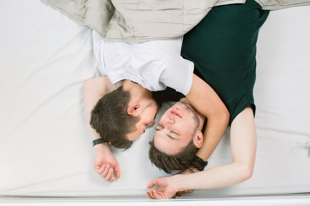 Giovani coppie gay che si trovano sul letto, vista superiore. San Valentino. Due ragazzi sexy sul letto.