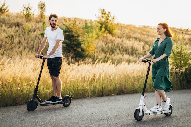 Giovani coppie in vacanza divertendosi guidando motorino elettrico sulla strada nella campagna.