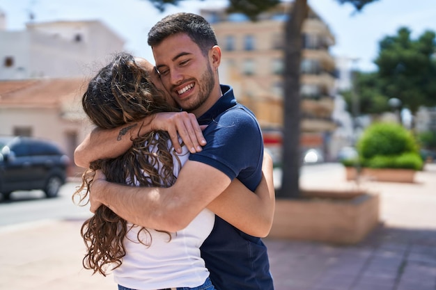 Giovani coppie ispaniche che sorridono fiduciose che si abbracciano al parco