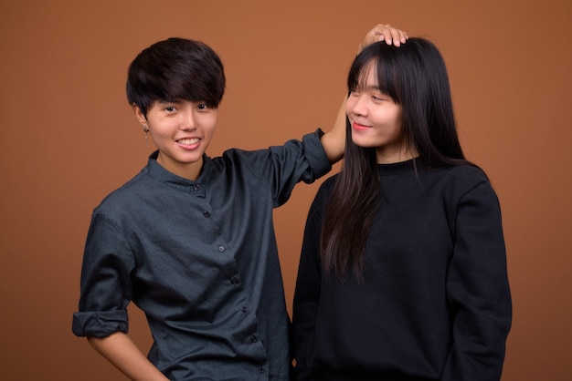 Giovani coppie lesbiche asiatiche insieme e innamorati contro il marrone