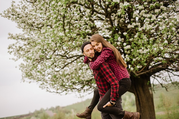 Giovani coppie romantiche che camminano sul prato e sull'albero in fiore e si divertono