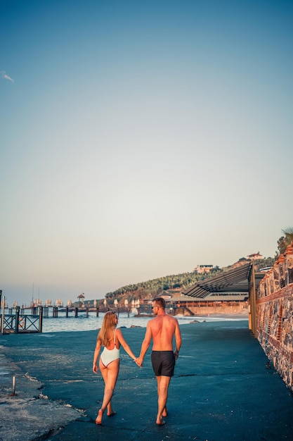 Giovani coppie romantiche innamorate che camminano insieme al tramonto lungo la spiaggia del Mediterraneo Vacanze estive in un paese caldo Coppia sposata felice in vacanza in Turchia Messa a fuoco selettiva