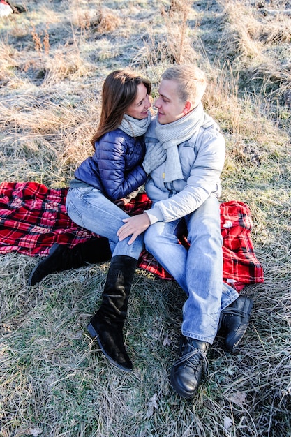 Giovani coppie sensuali di modo grazioso nell'amore che si siede nel campo di freddo di inverno