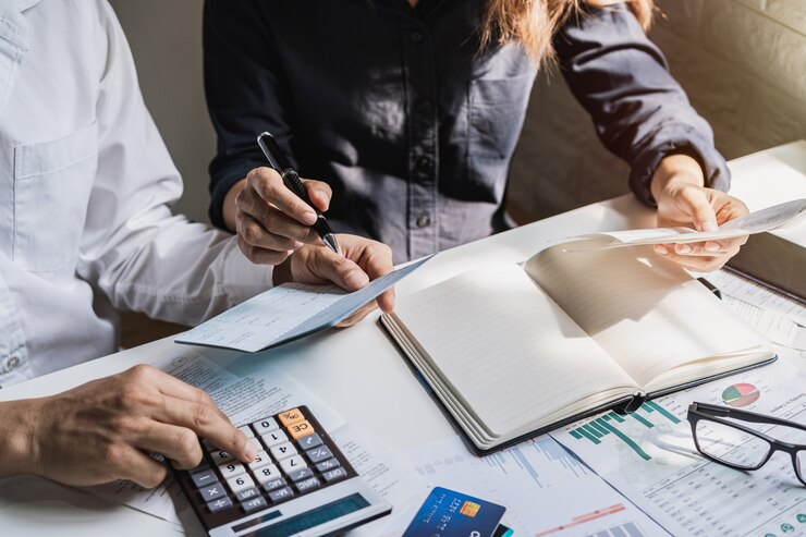 Giovani coppie sollecitate che controllano le fatture, le tasse, il saldo del conto bancario e il calcolo delle spese nel salone a casa