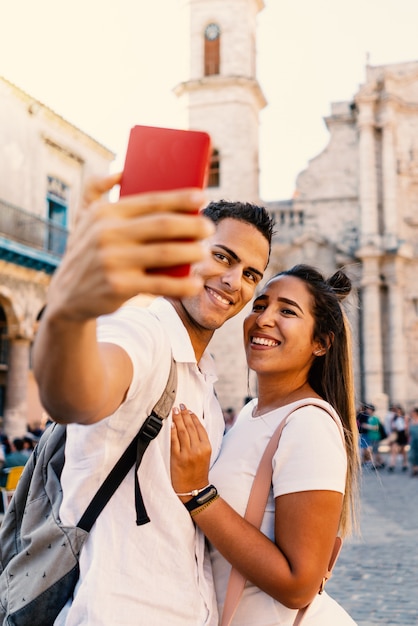 Giovani coppie sorridenti che prendono selfie con il telefono a Avana, Cuba.