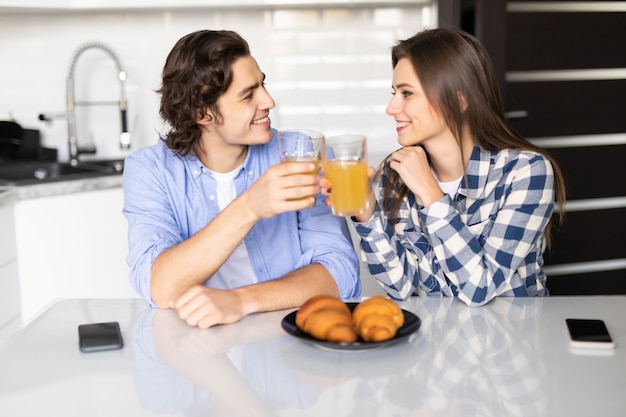 Giovani coppie sveglie che godono insieme della loro colazione in cucina