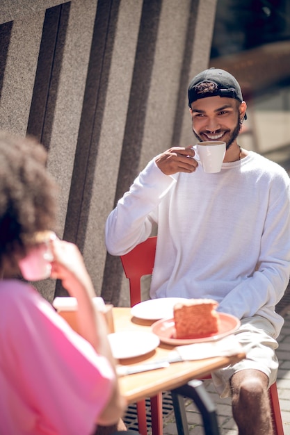 Giovani coppie sveglie che mangiano caffè nel caffè della via