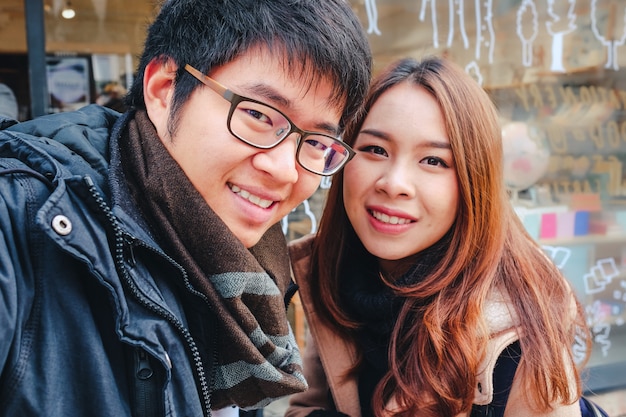 Giovani coppie turistiche asiatiche felici che prendono un selfie nella città