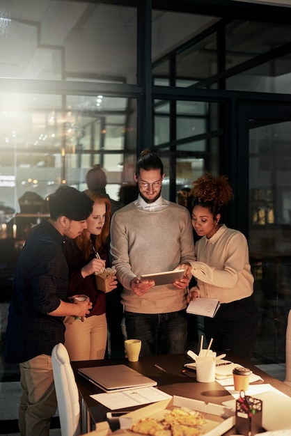 Giovani d'affari notturni e tecnologia tablet per pianificare la ricerca o la collaborazione in un ufficio buio Diversità idee digitali e lavorare fino a tardi online nel lavoro di squadra o nella produttività dell'agenzia di design