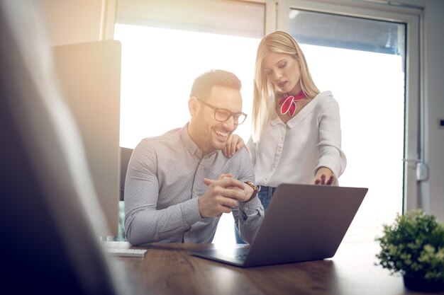 Giovani designer di successo che parlano del progetto e lavorano su un laptop in ufficio.