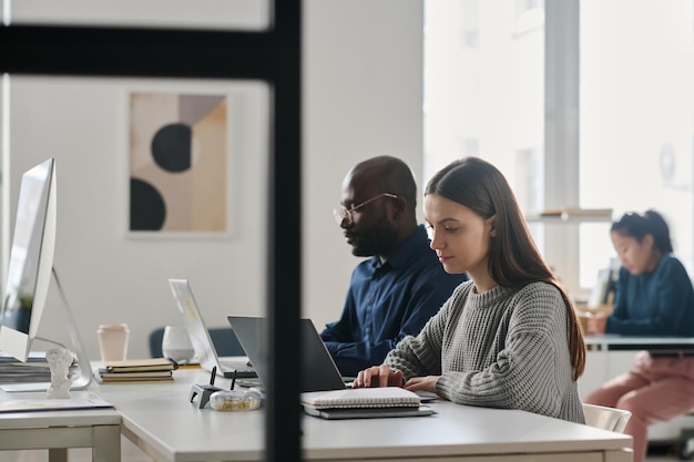 Giovani diversi che lavorano con i portatili in ufficio