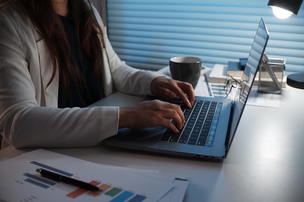 Giovani donne asiatiche che lavorano a tarda notte in una stanza buia usando il laptop