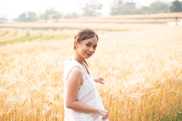 Giovani donne asiatiche in abiti bianchi in piedi nel campo di riso d'orzo