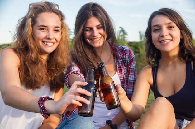 Giovani donne che bevono birra nel parco