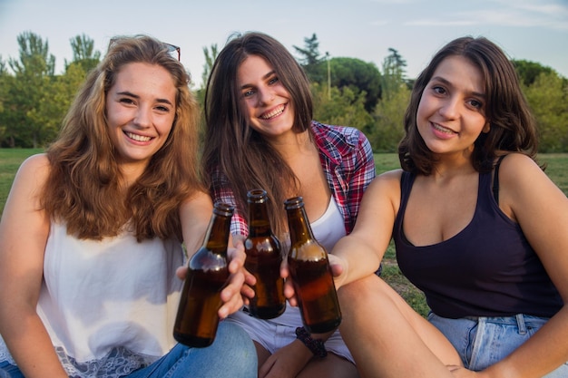 Giovani donne che bevono birra nel parco