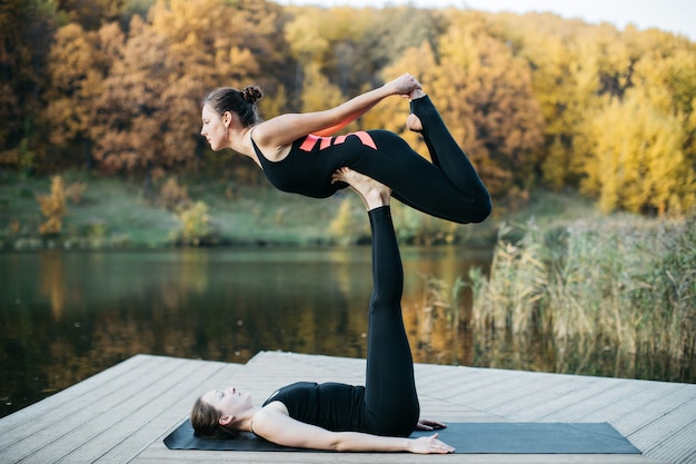 Giovani donne che fanno yoga asana in natura vicino al lago