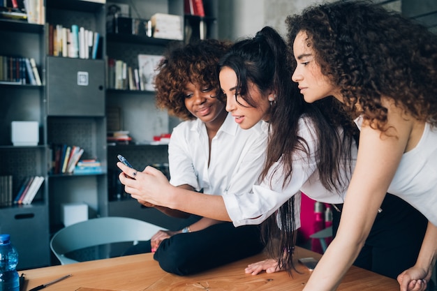 Giovani donne che giocano con lo smartphone in un ufficio moderno