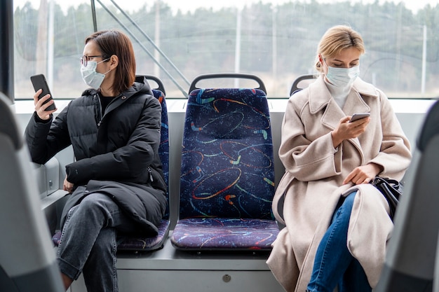 Giovani donne che utilizzano i mezzi pubblici con maschera chirurgica